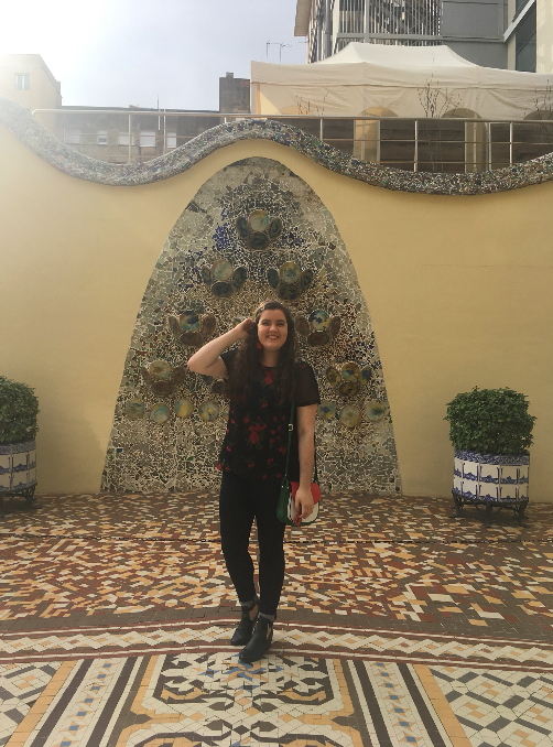 Sarah in front of a stone wall and mosaic tile floor in Spain