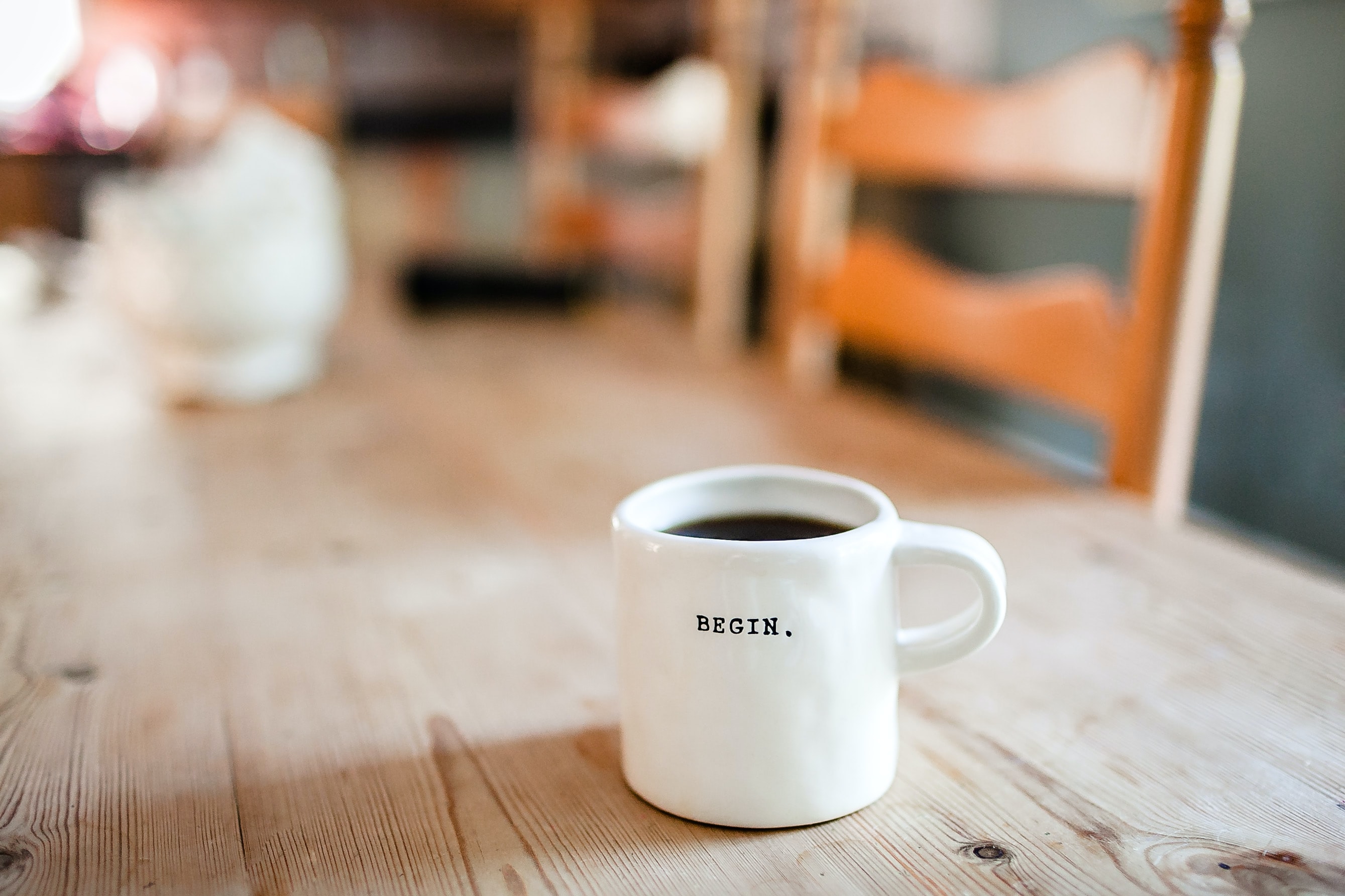 White coffee cup on table with the word "begin" on it